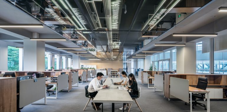 people wearing masks at a long desk in a high ceiling office